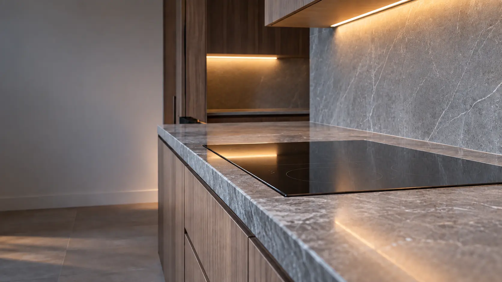A hillside house kitchen with an induction cooktop in a stone counter, seen low along the counter, the cooktop surface catching the light.
