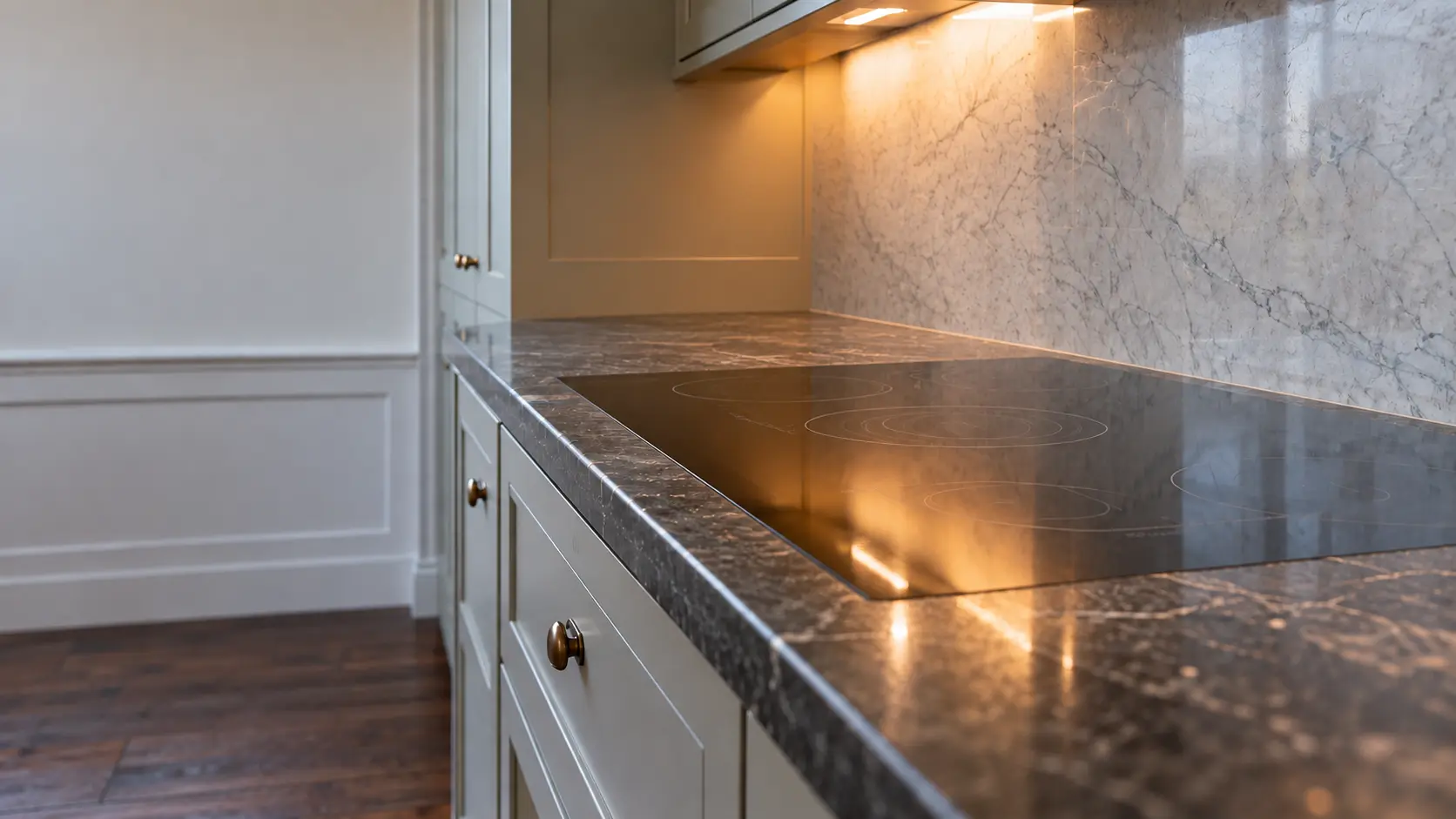 A Victorian flat kitchen with a compact induction cooktop, seen low along the counter, the cooktop surface catching the light.