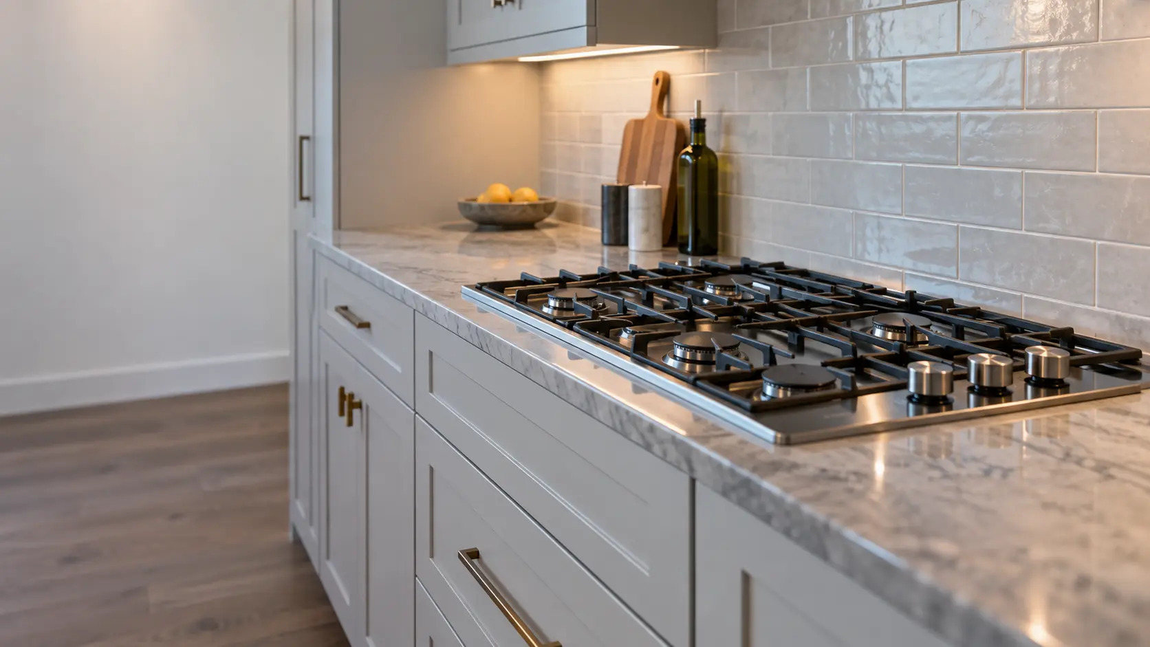 A slab-built house kitchen with a 36-inch gas cooktop, seen low along the counter, the cooktop surface catching the light.