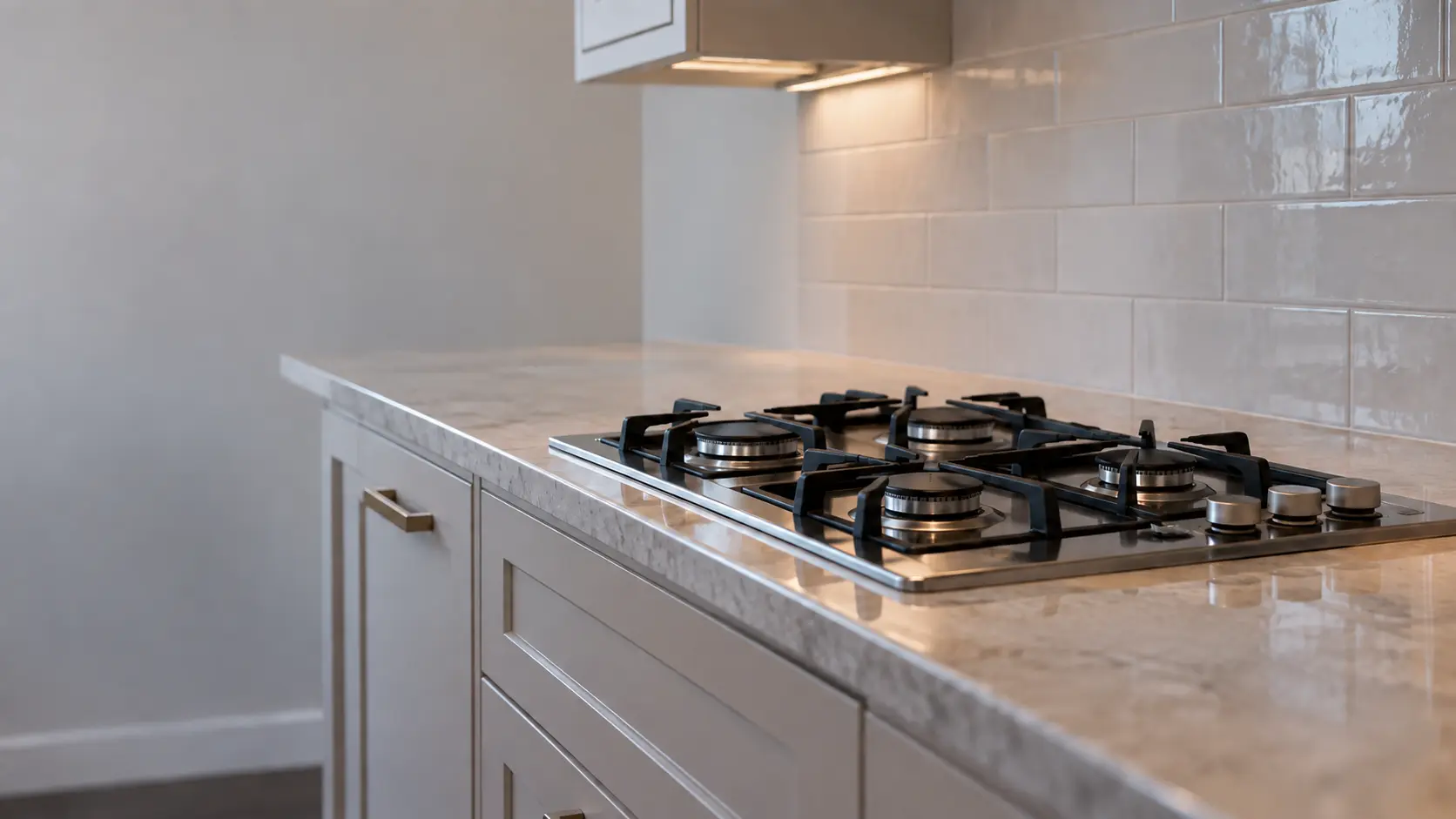 A semi-attached house kitchen with a four-burner gas cooktop, seen low along the counter, the cooktop surface catching the light.