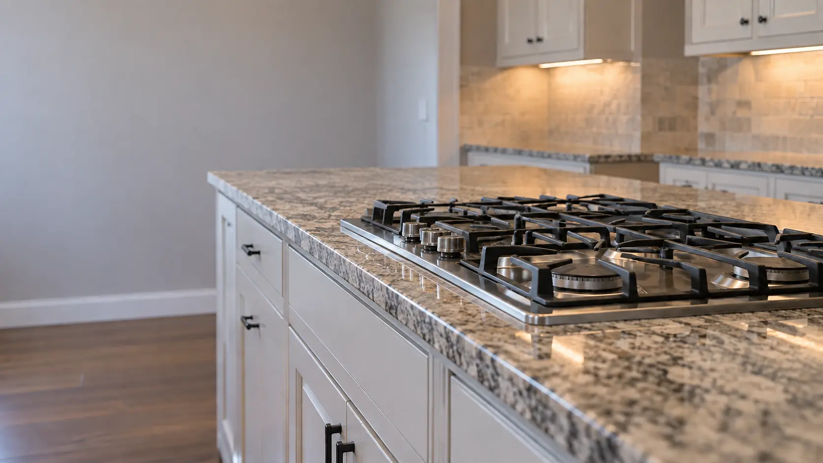 A detached house kitchen with a gas cooktop in a granite island, seen low along the counter, the cooktop surface catching the light.