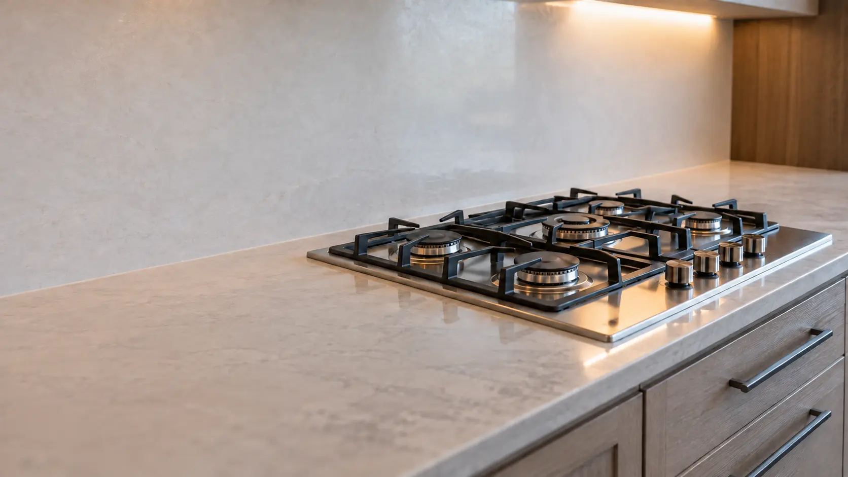 A family kitchen with a five-burner gas cooktop over drawers, seen low along the counter, the cooktop surface catching the light.