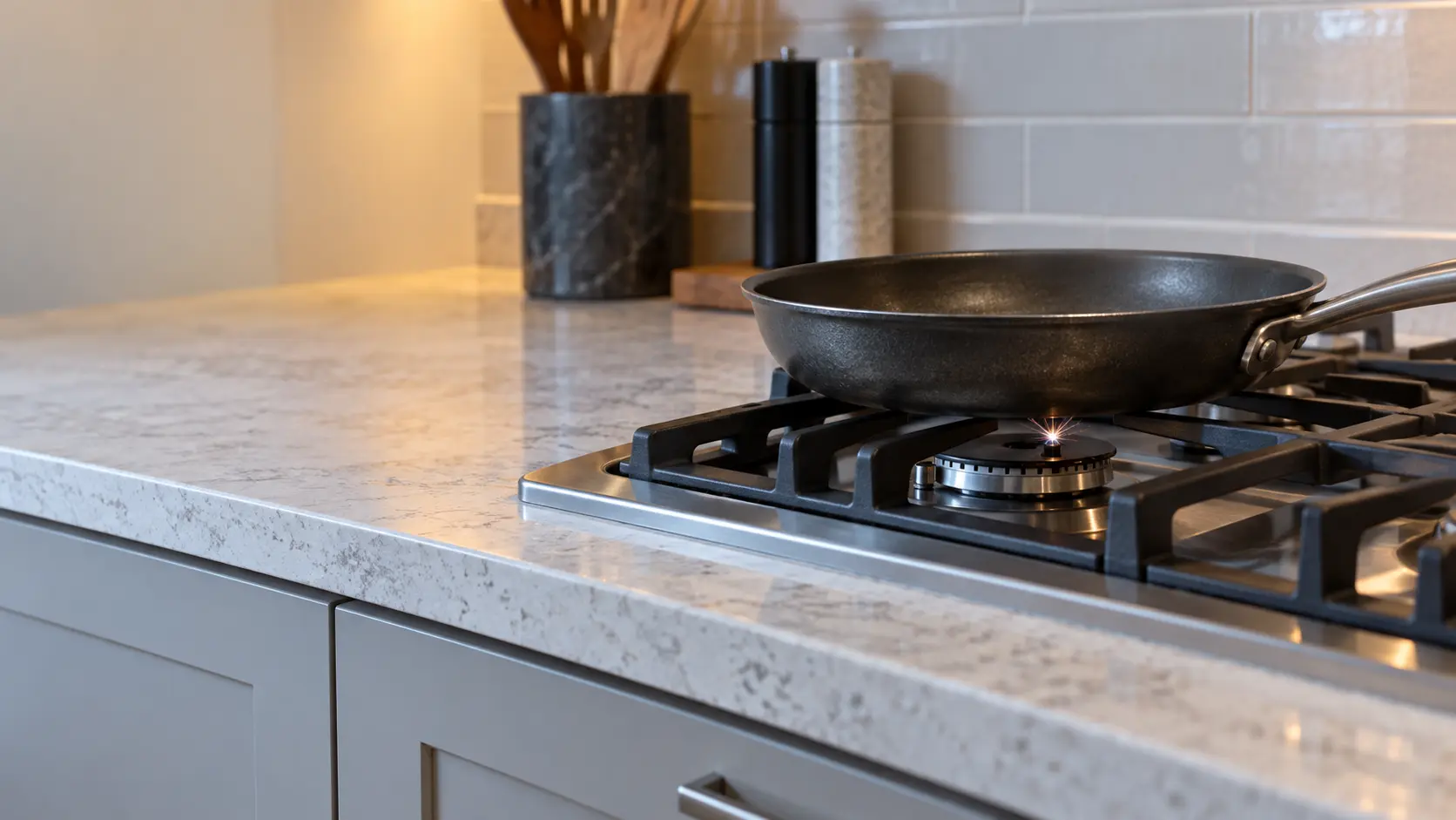 A gas cooktop burner clicking with a small spark and no flame, an empty pan above it.