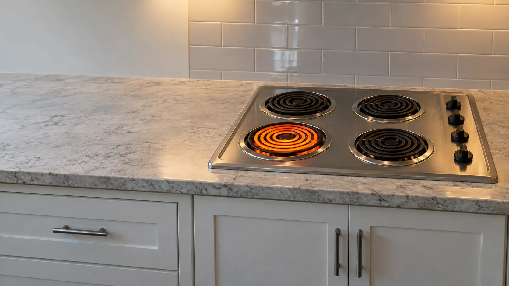 A US home kitchen with a coil electric cooktop set into a laminate countertop, one coil glowing bright orange with no pan on it while all its knobs sit at off, the counter around it cleared.