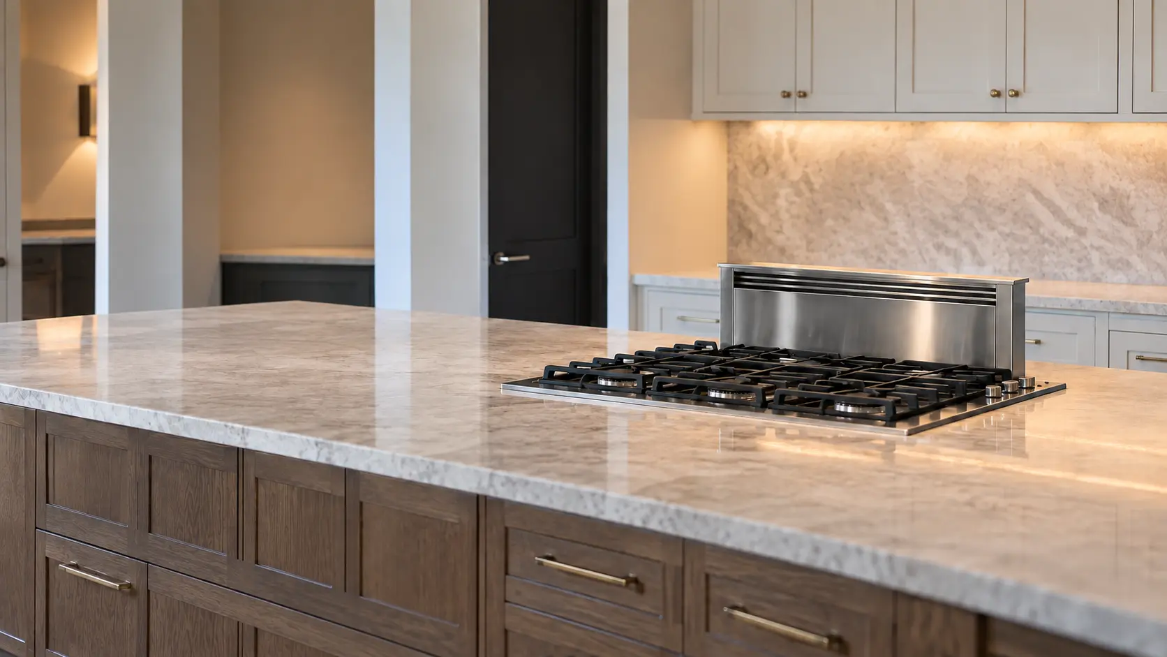 A built-in cooktop in a large Texas suburban kitchen with a 36-inch gas cooktop in an island with a downdraft vent behind it, seen from across the room.